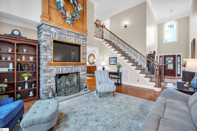 living room with hardwood / wood-style flooring, a fireplace, ornamental molding, and a high ceiling