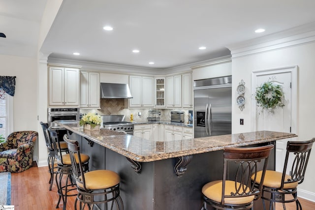 kitchen featuring tasteful backsplash, appliances with stainless steel finishes, light stone countertops, and a breakfast bar area