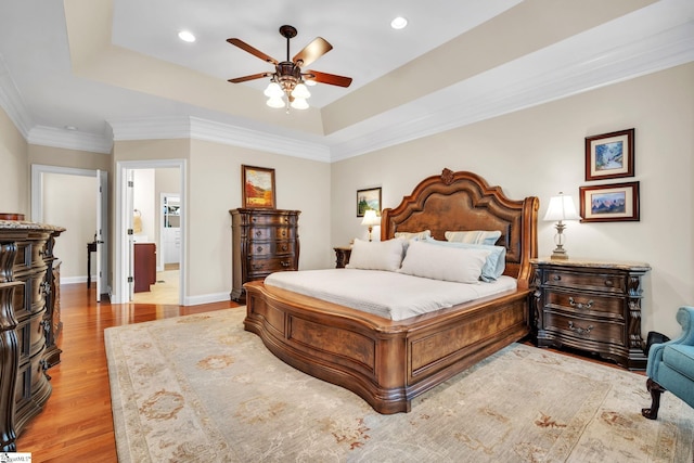 bedroom featuring connected bathroom, crown molding, light hardwood / wood-style flooring, a raised ceiling, and ceiling fan