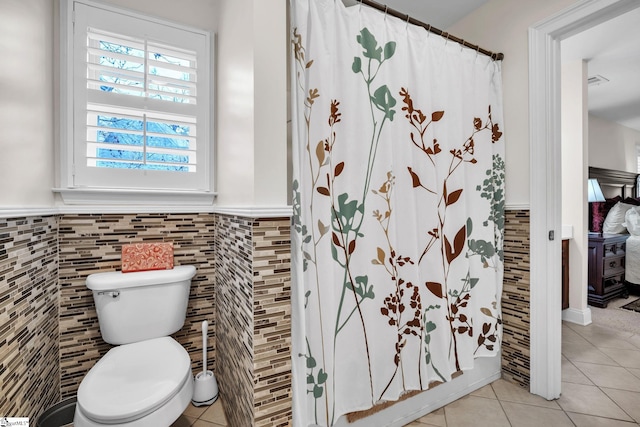 bathroom featuring tile patterned flooring, tile walls, and toilet