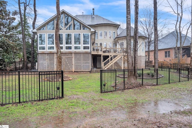 rear view of house with a wooden deck, a yard, and a sunroom