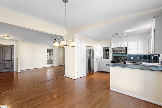 kitchen featuring tasteful backsplash, white cabinetry, sink, hanging light fixtures, and stainless steel appliances