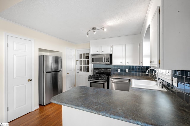 kitchen with sink, white cabinetry, appliances with stainless steel finishes, dark hardwood / wood-style flooring, and kitchen peninsula