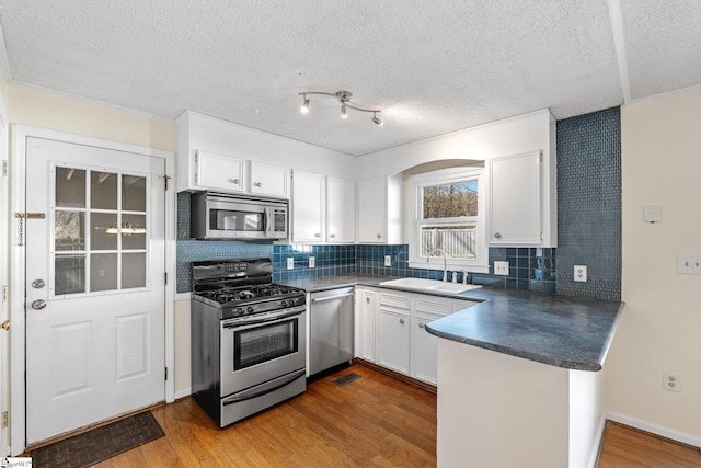 kitchen with white cabinetry, stainless steel appliances, sink, and wood-type flooring