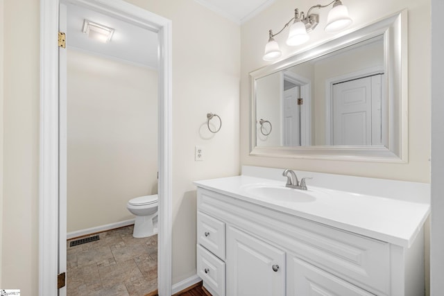 bathroom with vanity, ornamental molding, and toilet