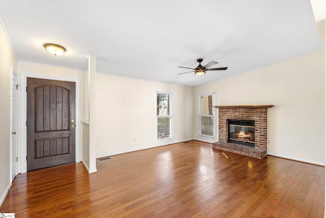 unfurnished living room featuring crown molding, hardwood / wood-style flooring, ceiling fan, a brick fireplace, and vaulted ceiling