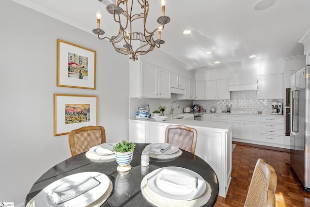 dining space with sink, dark parquet flooring, ornamental molding, and a chandelier