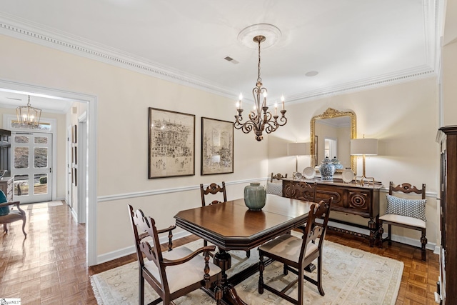 dining room featuring crown molding, parquet floors, and an inviting chandelier