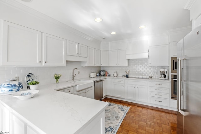 kitchen with appliances with stainless steel finishes, sink, white cabinets, kitchen peninsula, and light parquet flooring