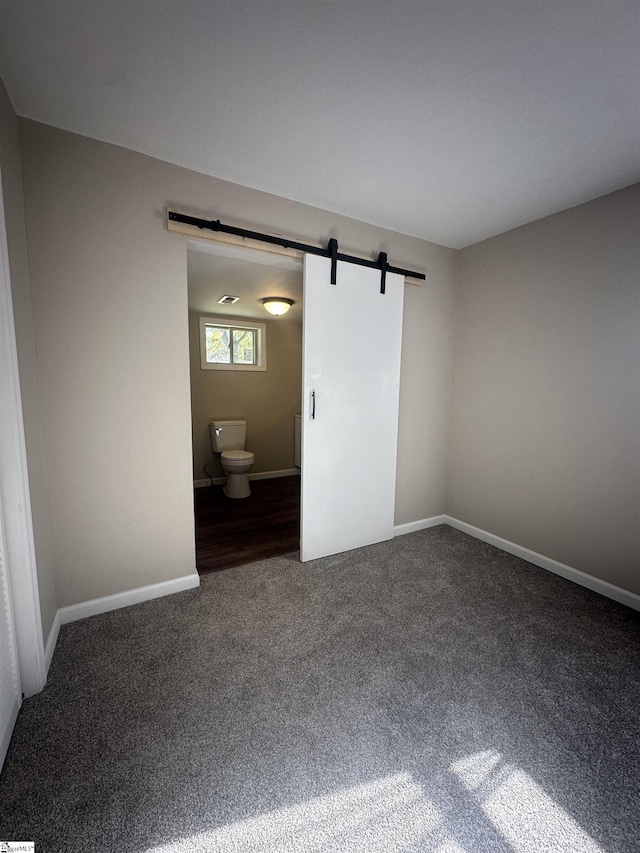 carpeted empty room with a barn door