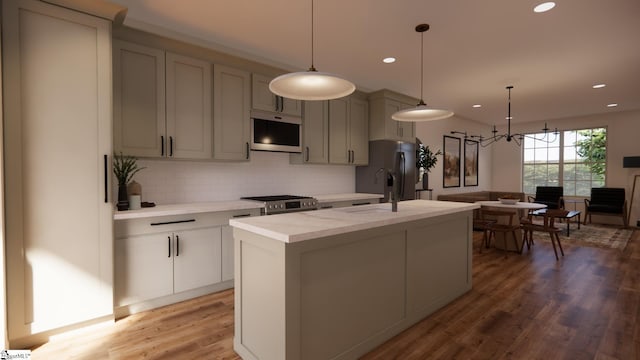 kitchen with hardwood / wood-style floors, decorative light fixtures, stainless steel appliances, and an island with sink