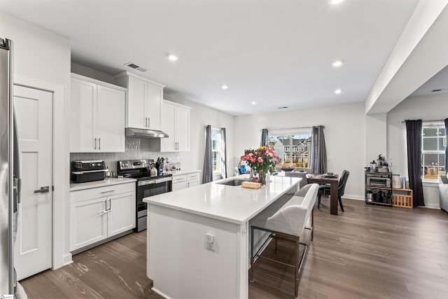 kitchen featuring white cabinetry, an island with sink, dark hardwood / wood-style flooring, decorative backsplash, and stainless steel range with electric cooktop