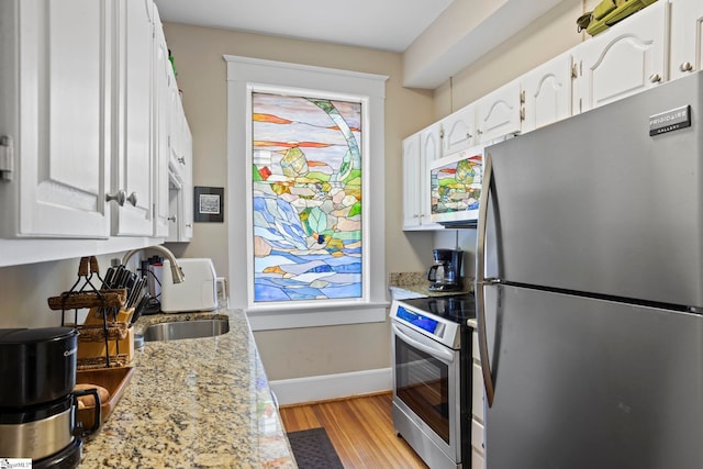 kitchen with stainless steel appliances, light stone countertops, and white cabinets