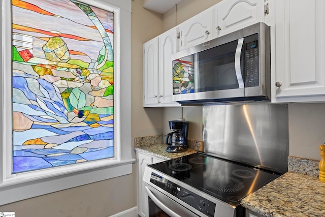 kitchen with light stone countertops, appliances with stainless steel finishes, and white cabinets