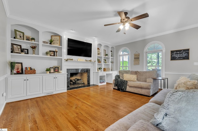 living room featuring ornamental molding, a high end fireplace, and light hardwood / wood-style flooring