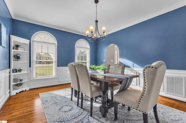 dining room with an inviting chandelier, crown molding, and light hardwood / wood-style flooring