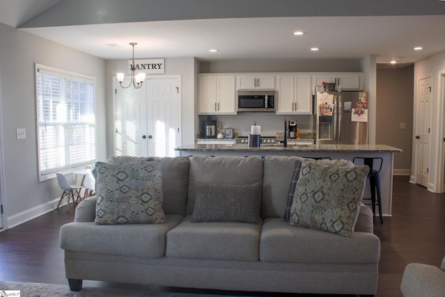 living room featuring a notable chandelier and dark wood-type flooring