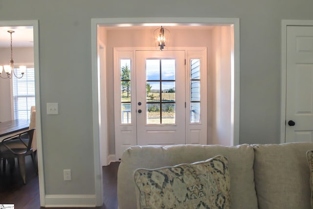 doorway with a notable chandelier and hardwood / wood-style floors