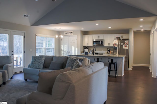 living room with high vaulted ceiling, dark hardwood / wood-style floors, sink, and an inviting chandelier