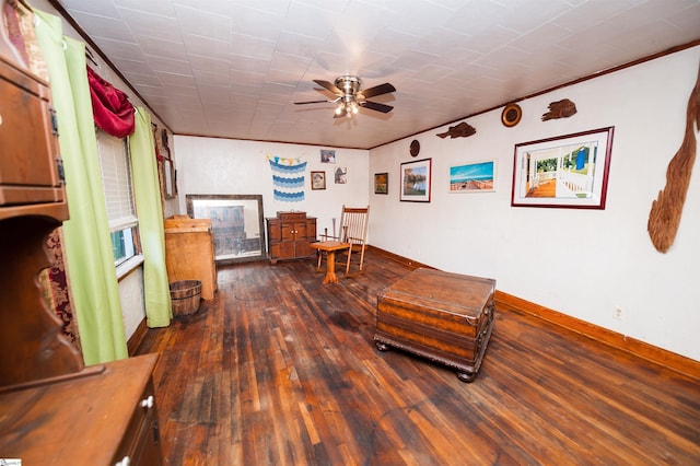 living area with ornamental molding, dark hardwood / wood-style floors, and ceiling fan