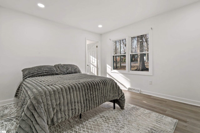 bedroom with hardwood / wood-style flooring and multiple windows