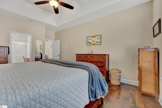 bedroom with ceiling fan, dark hardwood / wood-style floors, ensuite bath, and a raised ceiling