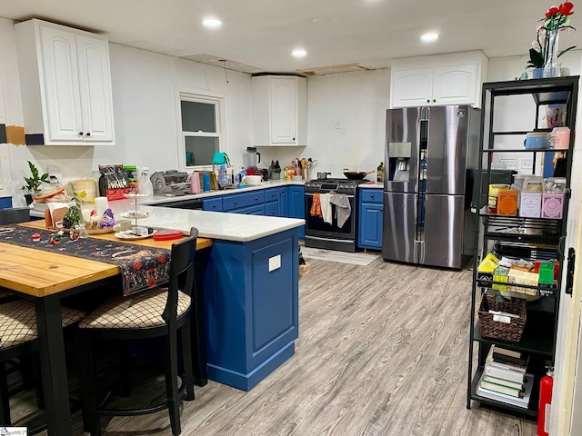 kitchen with blue cabinets, light hardwood / wood-style flooring, kitchen peninsula, stainless steel appliances, and white cabinets