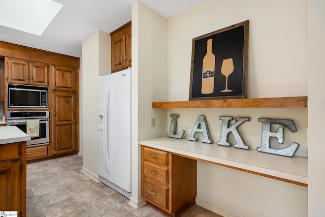 kitchen featuring stainless steel oven, white refrigerator with ice dispenser, light tile patterned floors, a skylight, and black microwave