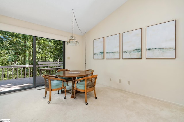 carpeted dining space featuring vaulted ceiling