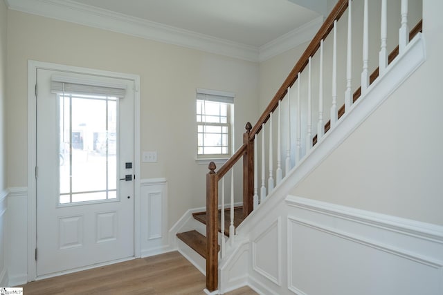 foyer entrance with ornamental molding and light wood-type flooring