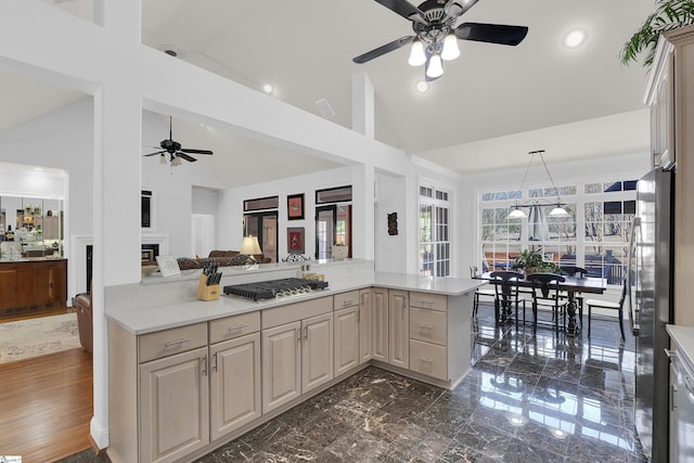 kitchen with kitchen peninsula, stainless steel appliances, ceiling fan, high vaulted ceiling, and light brown cabinets