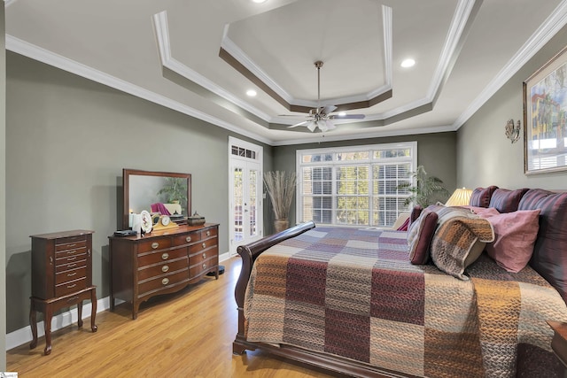 bedroom featuring ceiling fan, ornamental molding, light wood-type flooring, and a raised ceiling