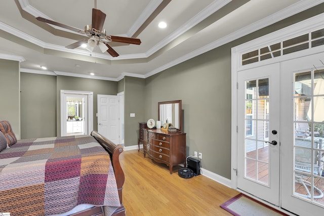 bedroom with light wood-type flooring, french doors, access to exterior, a raised ceiling, and crown molding