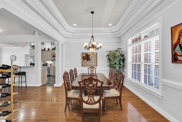 dining space with dark wood-type flooring, crown molding, and a chandelier