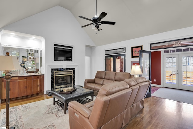 living room featuring light hardwood / wood-style flooring, french doors, ceiling fan, a fireplace, and high vaulted ceiling