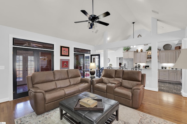 living room featuring high vaulted ceiling, light wood-type flooring, french doors, and ceiling fan