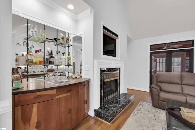 bar with a fireplace, dark wood-type flooring, french doors, and ornamental molding