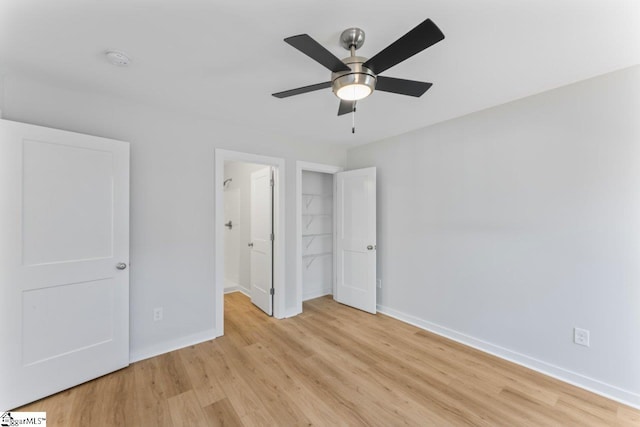 unfurnished bedroom featuring ceiling fan, light hardwood / wood-style flooring, a closet, and a spacious closet