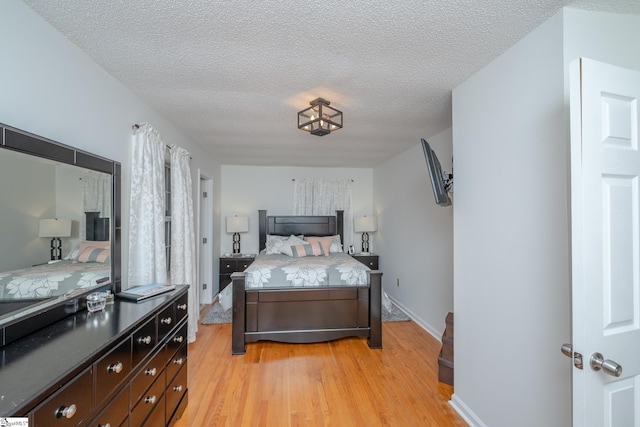 bedroom with a textured ceiling and light hardwood / wood-style flooring