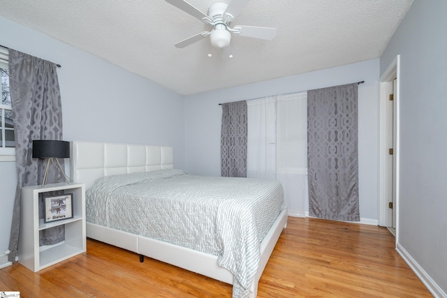 bedroom with hardwood / wood-style flooring, ceiling fan, and a textured ceiling