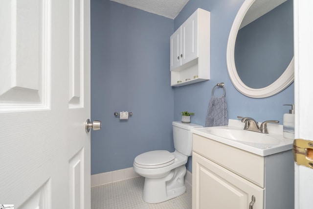 bathroom featuring tile patterned flooring, vanity, toilet, and a textured ceiling