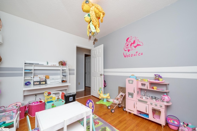 recreation room featuring hardwood / wood-style floors and a textured ceiling