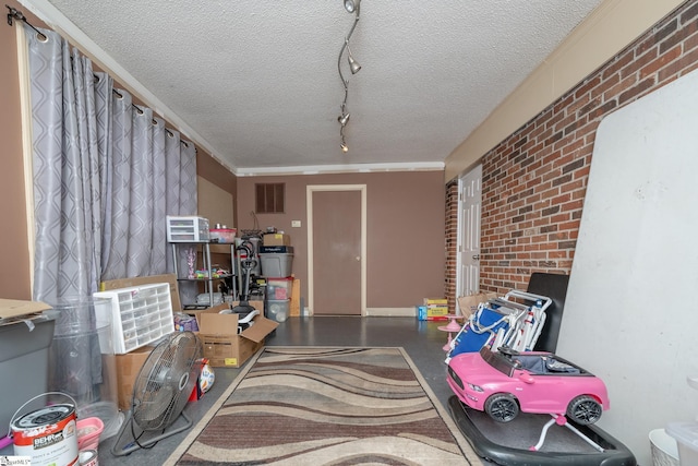 interior space featuring track lighting, brick wall, and a textured ceiling