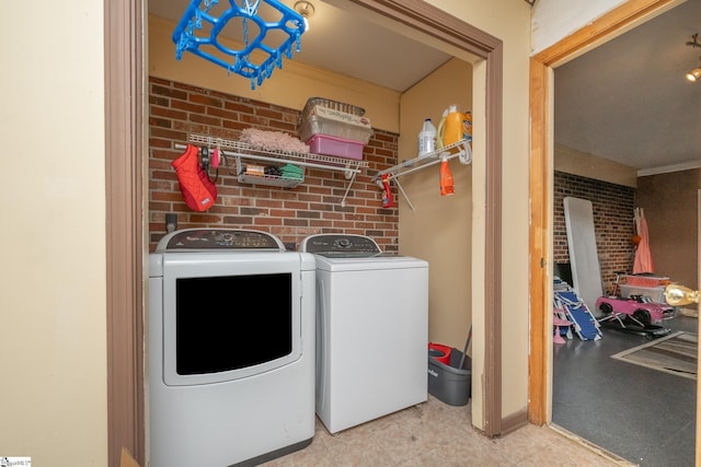 laundry area with washing machine and dryer and brick wall