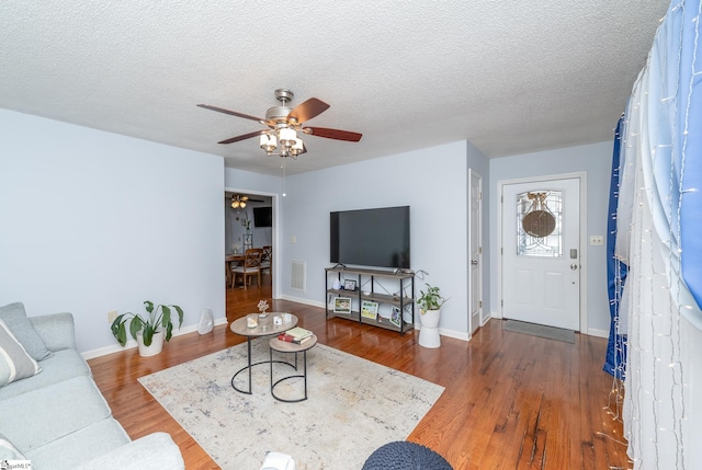 living room with a textured ceiling, hardwood / wood-style floors, and ceiling fan