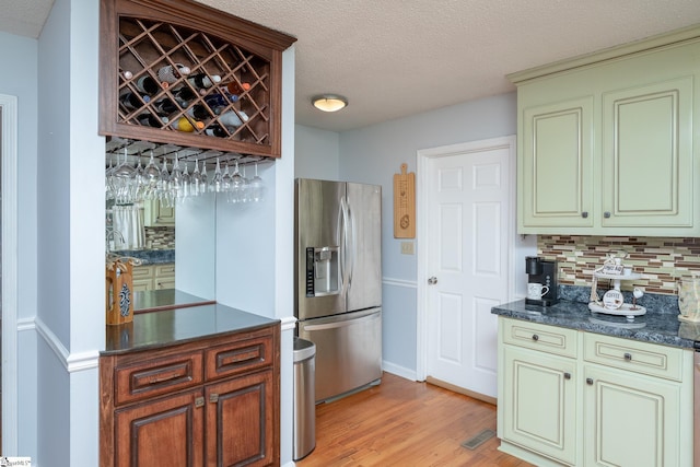 kitchen featuring light wood-type flooring, backsplash, a textured ceiling, and stainless steel fridge with ice dispenser