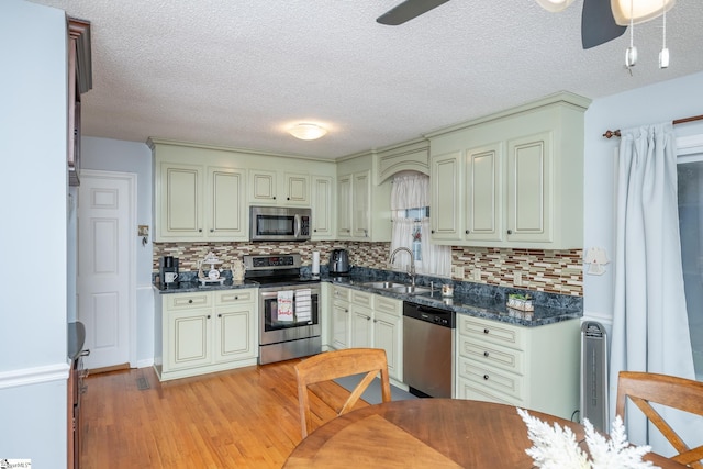 kitchen featuring ceiling fan, stainless steel appliances, light wood-type flooring, and sink