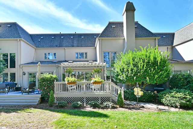 back of property featuring a lawn, a pergola, and a wooden deck