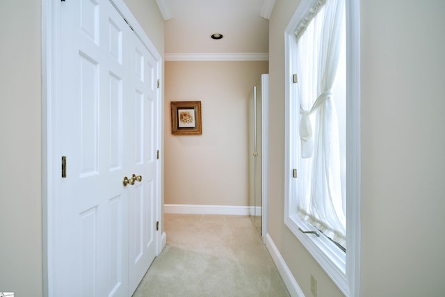 hallway featuring ornamental molding and light colored carpet