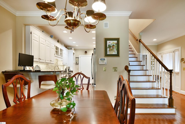 dining room featuring hardwood / wood-style flooring, sink, a chandelier, and crown molding